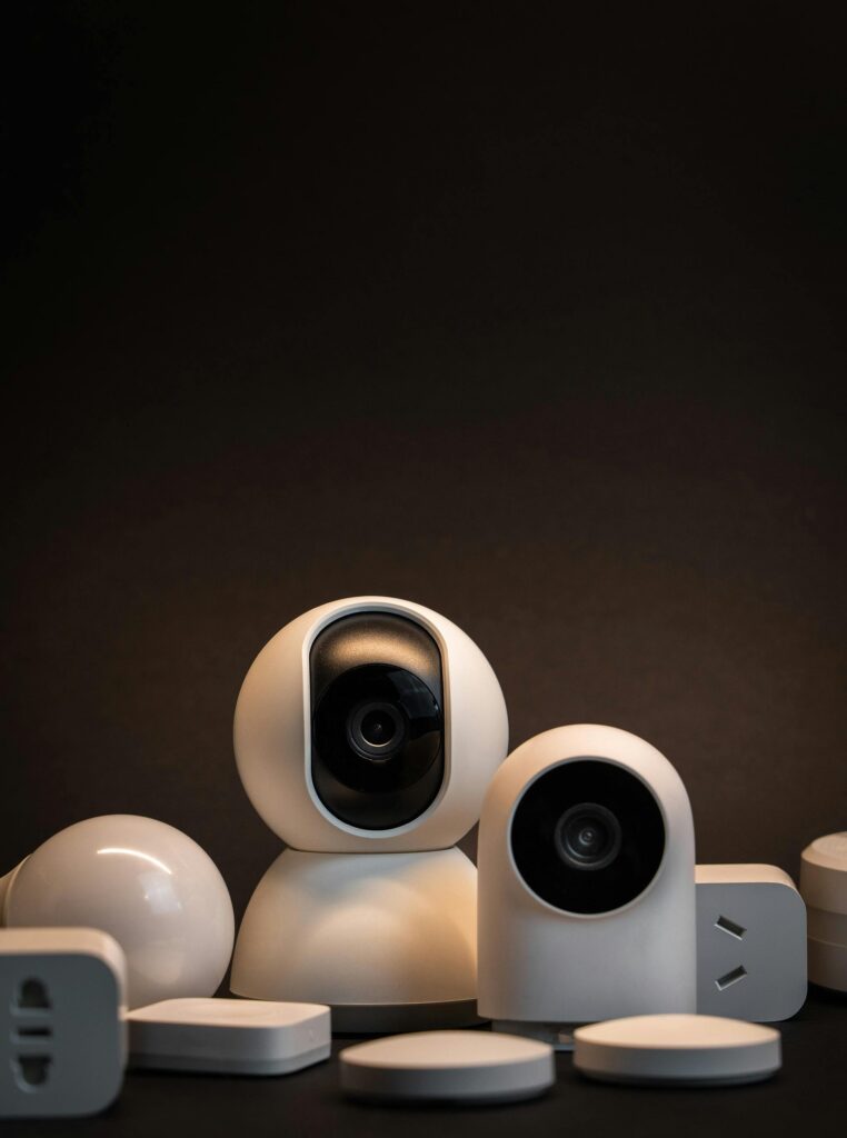 Close-up of modern white security cameras and smart home devices with dark background.